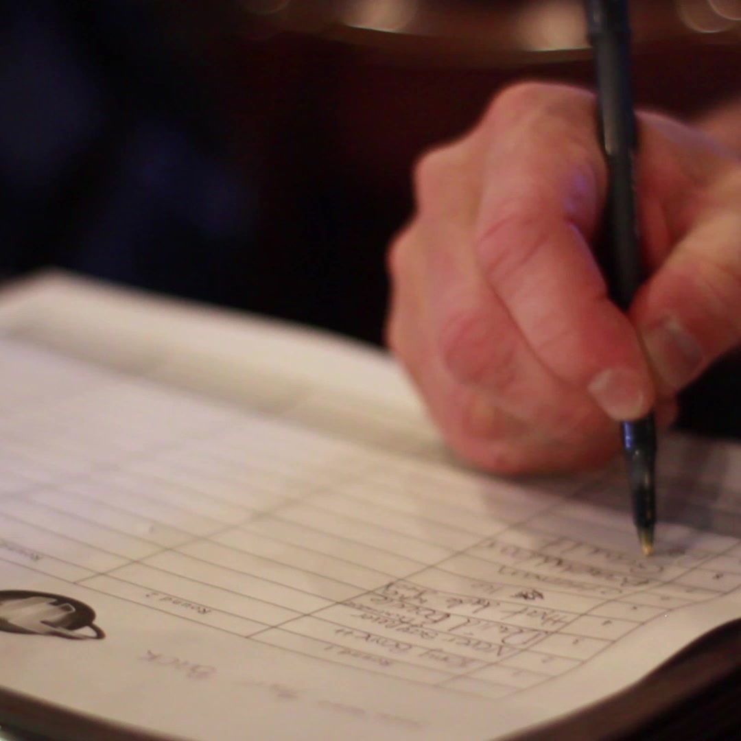 Close-up of a trivia player writing answers on a Magic Mike Entertainment trivia sheet